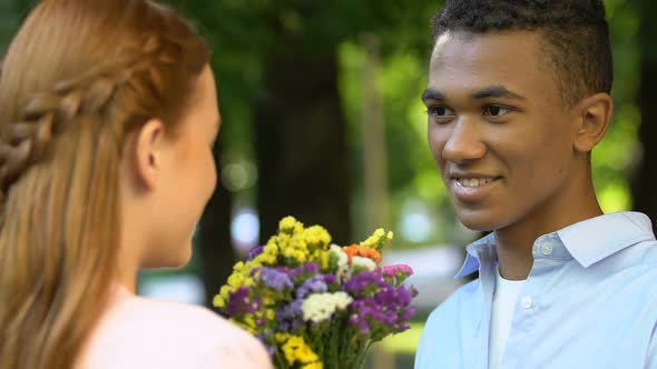 Male Teen Giving Flowers to Cute Girl in Park, Declaration of Love, Magic Moment