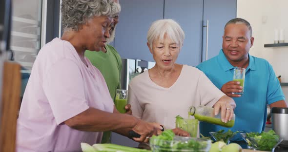 Happy senior diverse people making healthy drink in kitchen at retirement home