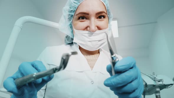 Dentist Woman Doctor Is Holding Dental Instruments Forceps and Needle in Hands and Looking at Camera