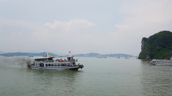 Passenger boat with dark fumes traveling along Halong Bay in Vietnam