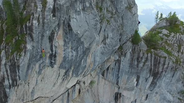 Aerial drone view of a man rock climbing up a mountain