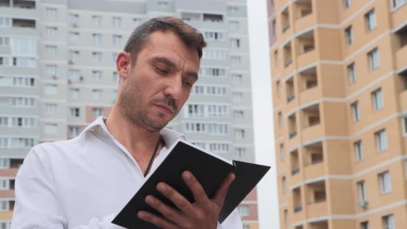 A Businessman in a White Shirt Makes Notes in a Notebook Thinks and Wonders