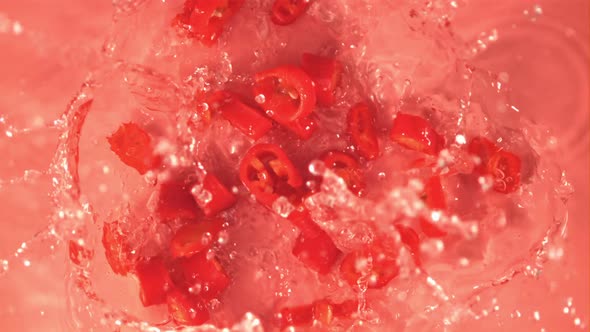 Super Slow Motion Sliced Red Chilli Pepper Falls on the Water with Splashes