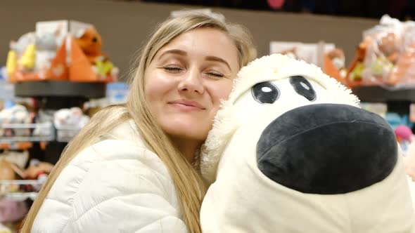 A Beautiful Young Girl Hugs a Big Soft Toy Dog