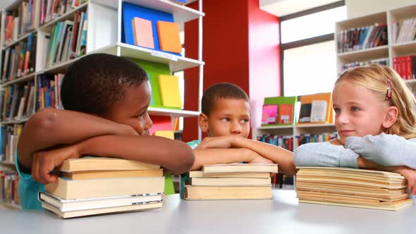 School kids leaning on stack of books in library