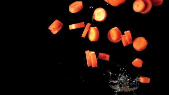 Super Slow Motion Pieces of Carrot Fall Into the Water with Splashes