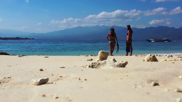 Girls happy and smiling on relaxing coastline beach vacation by blue green ocean with clean sand bac