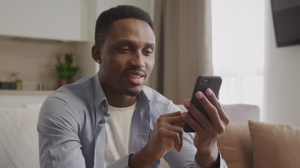 Africanamerican Adult Man Thinking and Typing a Reply with Smile on His Smartphone