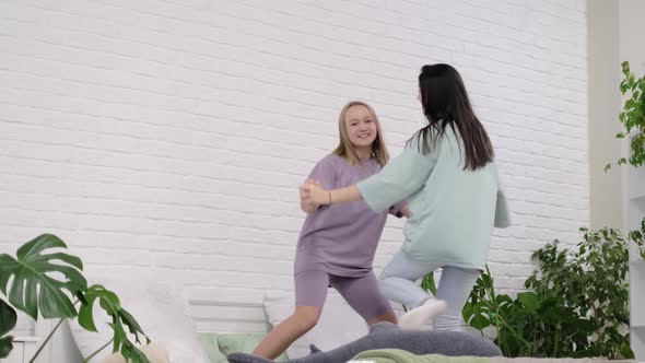 Young Girls Dancing on the Bed at Home