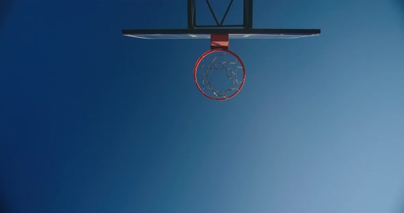 Basketball Players Throw Ball Into Basket Against Blue Sky
