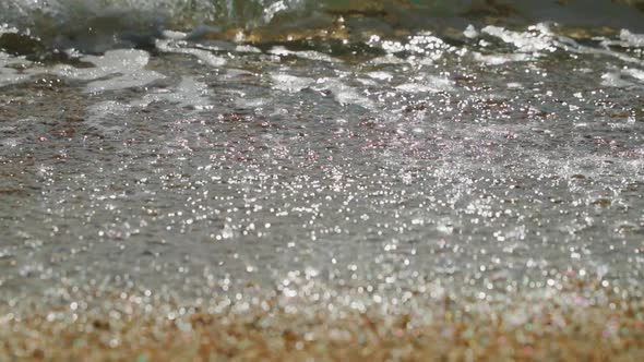 Closeup Slow Motion Footage of Beach of Gravel the Coarse Sand Waves Run on Sand Wet Stones Glint in