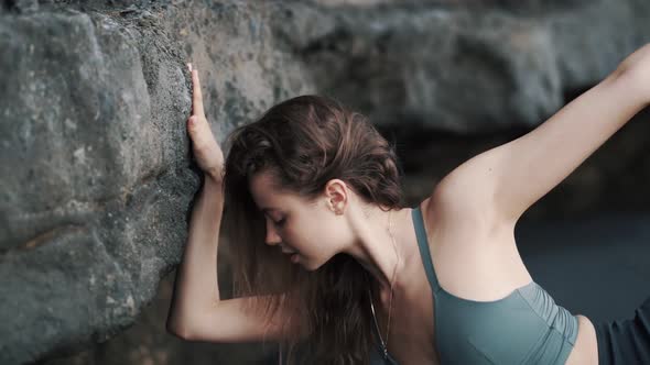 Woman Doing Stretching Exercises on Black Sand Beach Near Cliff Slow Motion