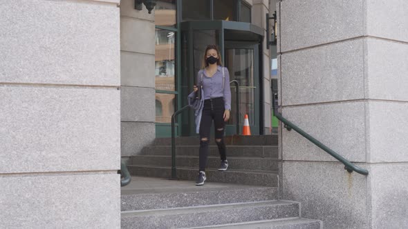 Slim woman walks down steps wearing black face mask to stop covid-19 spread