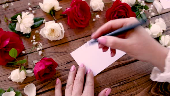 Writing BE HAPPY on a card near flowers close up