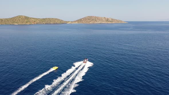 Aerial View of a Motor Boat Towing a Tube. Elounda, Crete, Greece