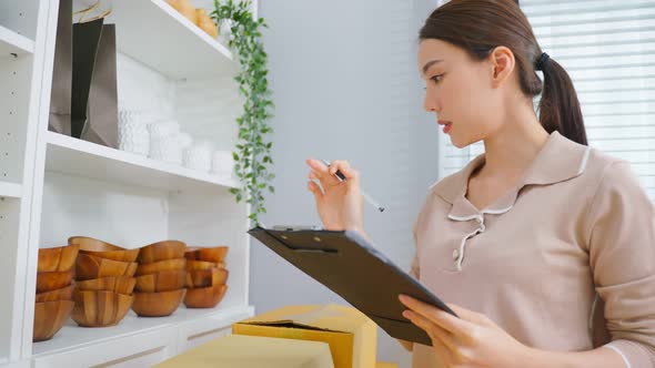 Asian beautiful woman check vase goods order for customer from shelf.