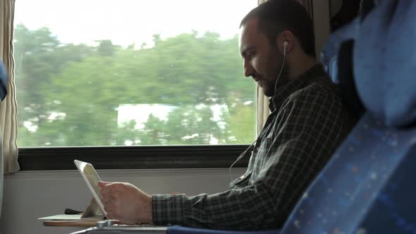 Serious Man Watching News on a Tablet in a Train