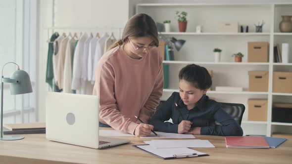 Young Womanmentor Helping Teenage Girl Study Do Homework Using Laptop at aTable