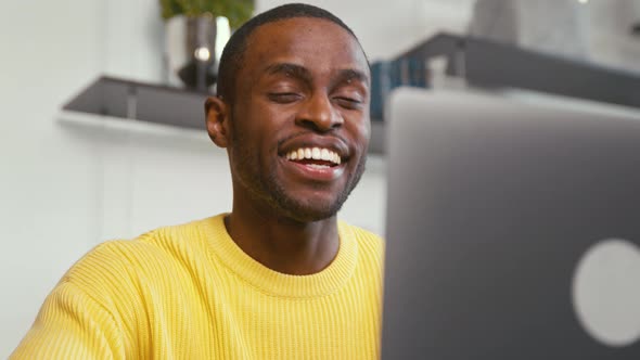 Smiling man calling with webcam at the desk at home office
