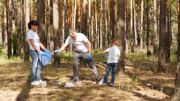 Happy Family Collects Garbage in the Forest. Dad and Son Put the Garbage in a Bag