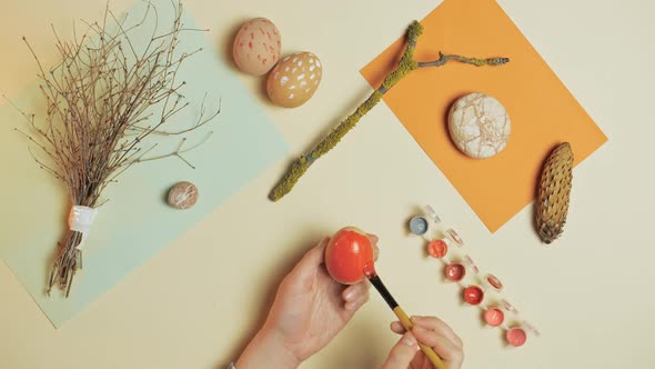  Woman paints an egg with red paint