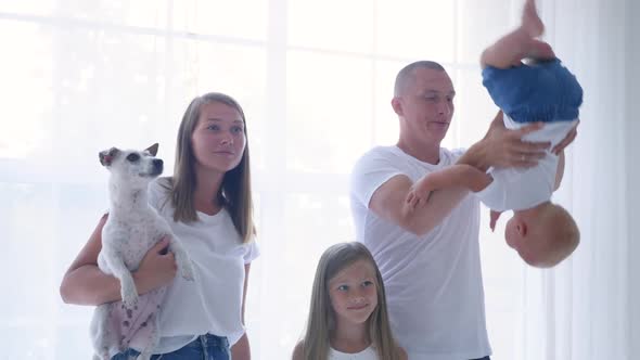 Family of Four Stands in a White Room Against