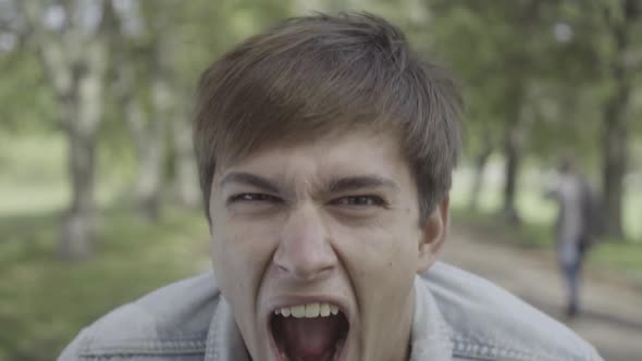 Closeup Face of Furious Young Man Screaming Outdoors