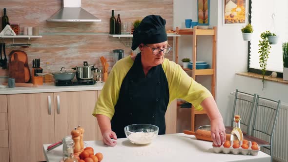 Woman Breaks Egg Above White Flour