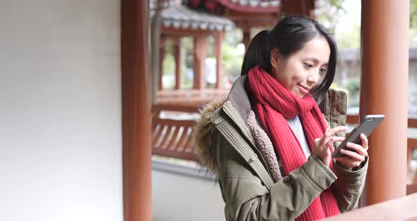 Young asian woman using smart phone in china, beautiful chinese pavilion garden