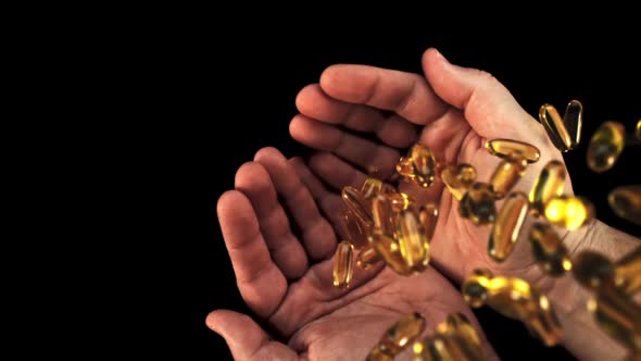 Capsules of Vitamin Omega 3 Fall Into the Hands of a Man