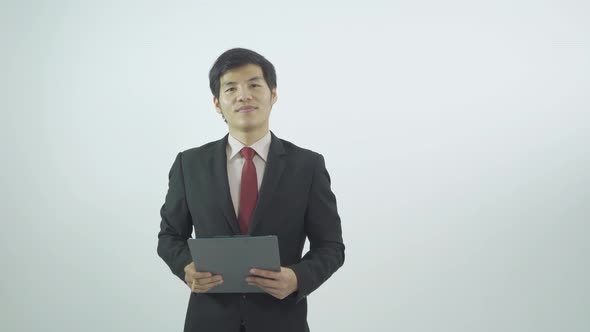 Young Asian business man standing and taking notes on paper notepad