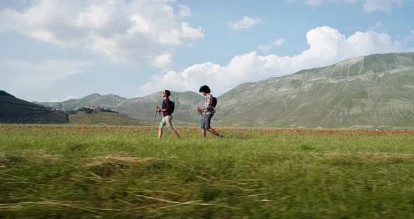 Aerial View Flying Above Two People Couple Hiking or Nordic Walking Outdoor on a Trail Path Near