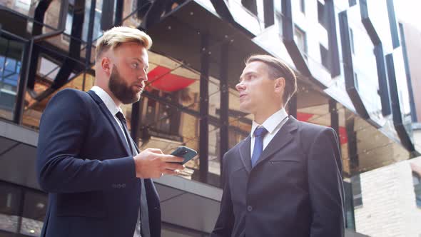 Confident businessman and his colleague in front of modern office building.