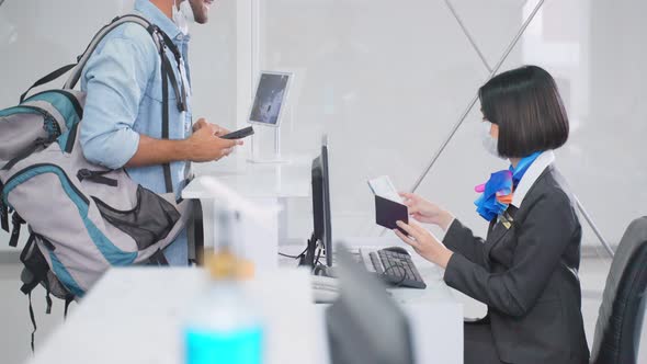 Male traveler wear face mask, give passport to female officer at airline check in counter in airport