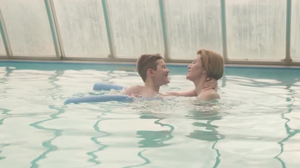 Mother teaching seven-year-old son to swim in the swimming pool.