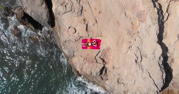 Aerial, top down, drone shot of a woman lying on a towel in Mallorca, Spain