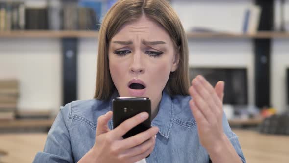Creative Woman Reacting to Loss While Using Smartphone