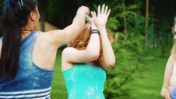 friends throw colorful powder at red haired young woman at Holi festival