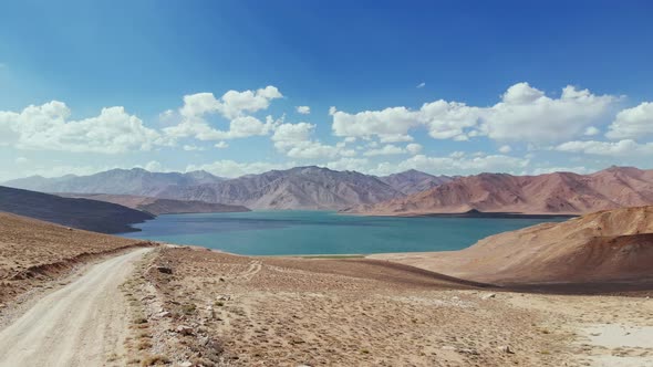 Aerial Over Gravel Road Path Toward Bulunkul Lake in Sunny Day