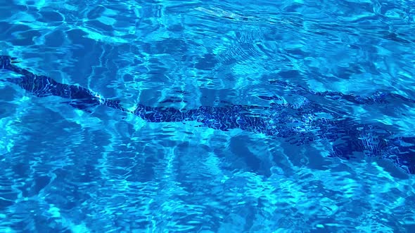 Water surface of a swimming pool. Water is moving making many reflections and ripples in an abstract