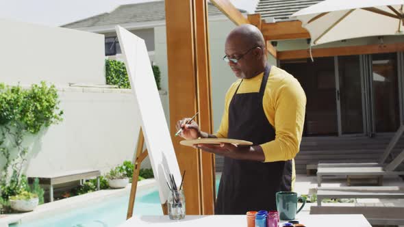 African american senior man standing on a terrace and painting