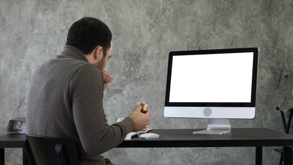 Young man choking while eating and watching something on