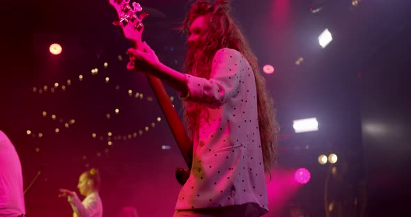 Woman Guitarist at a Rock Concert Plays Electric Guitar on the Open Stage