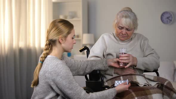 Young Lady Bringing Painkillers to Grandmother Feeling Stomach Ache, Health-Care