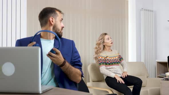 Beautiful Blonde Woman Watches TV and Makes Noise While Her Partner in Blue Jacket Tries To Work on