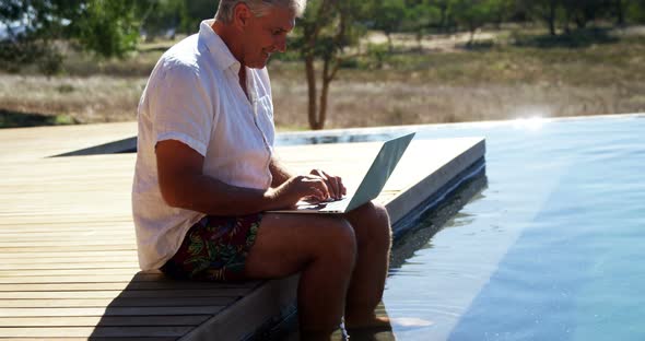 Man using laptop near poolside 4k