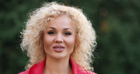 Attractive Girl in a Red Coat with Lips Turns To Camera and Smiles