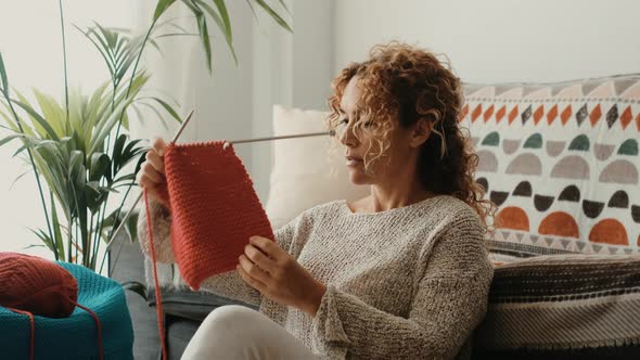 Young woman picking wool from basket while sitting on floor at home. Beautiful woman knit work