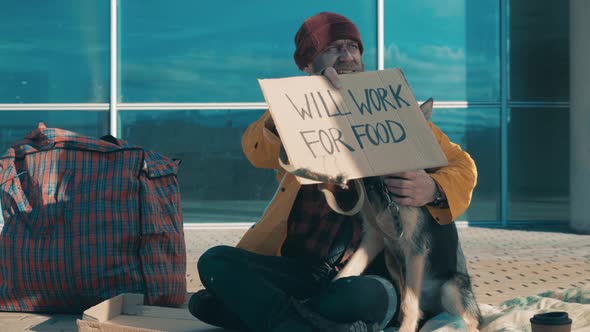 A Beggar is Sitting on the Ground with His Dog