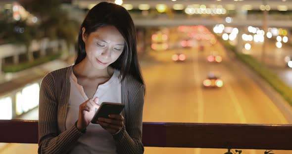 Woman using smart phone in the city at night 